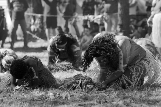 3 aboriginal dances kneel with their head towards the ground in dance