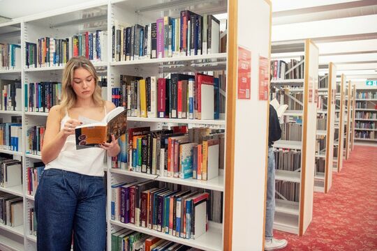 Woman reading in the shelves at State Library of Queensland