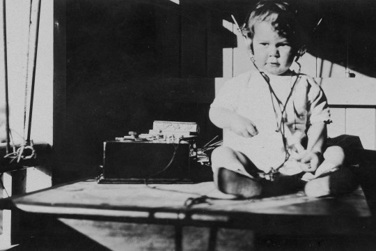 Young child listening to a radio 1920-1930