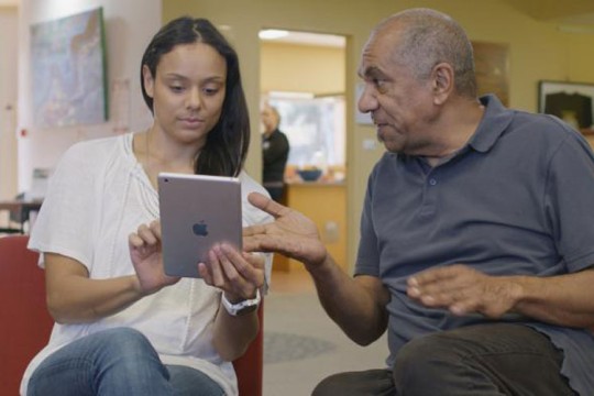 Woman using an iPad while a man gestures towards it.