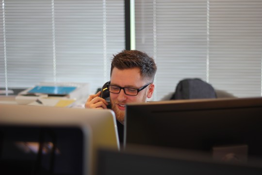 Man sitting behind computer screens, on the phone