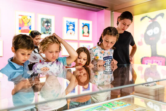 Group of kids looking at children's paintings.