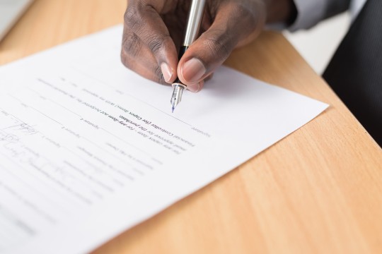 A hand signing a legal document