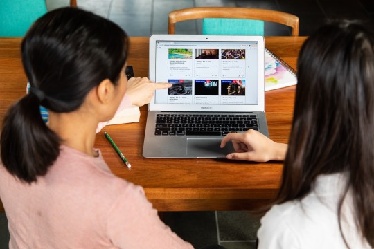 Two female students sitting at a desk, using a laptop