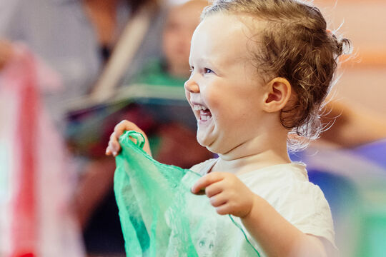 Happy child playing with a piece of fabric