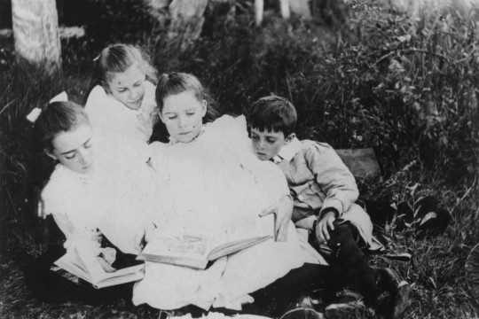 Group of children sitting on the grass reading books ca1900-1910 