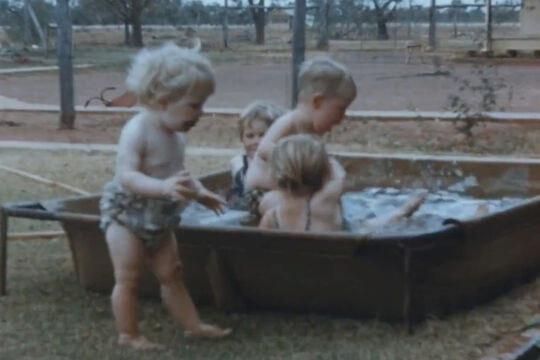 Four toddlers playing in water outside