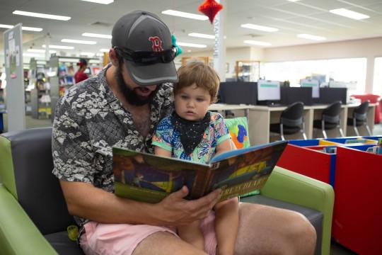 Dad and child reading a book in the library 
