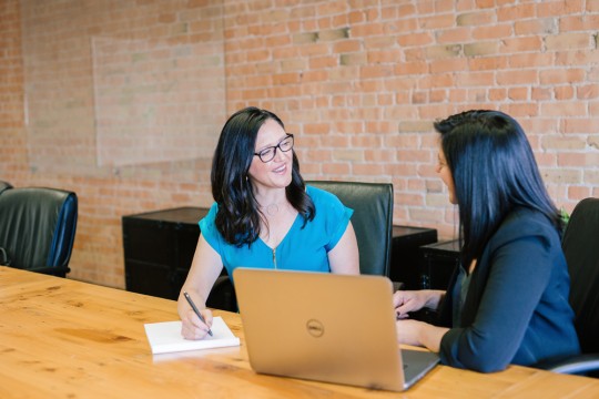 Two people talking and sitting at an office table. 