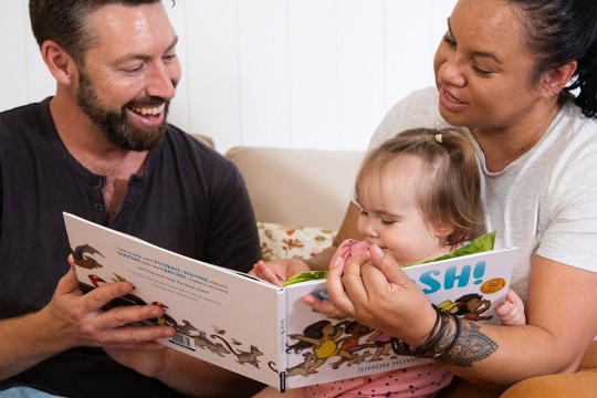 Family reading to small child at home