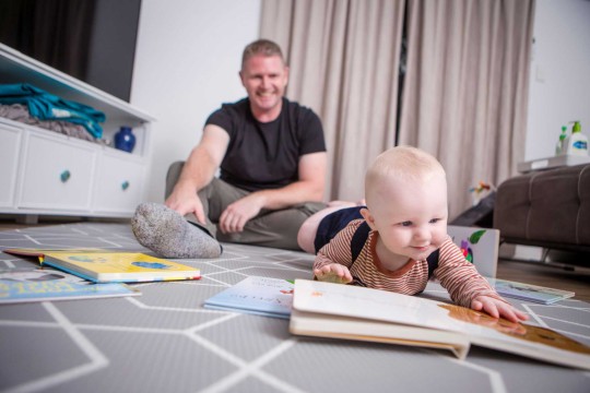 Baby and dad lying on floor with books