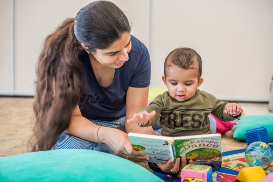 Parent and baby reading together in The Corner