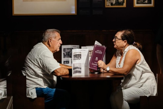 A couple sitting at the booth within the Meet me at the Paragon exhibition at State Library.