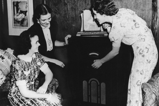 Three ladies gathered around an old fashioned radio