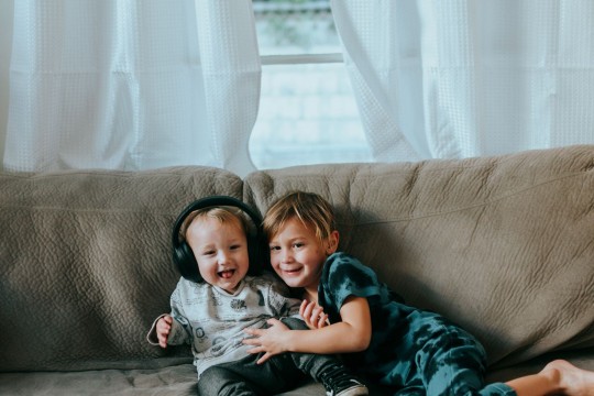 Siblings on couch listening with headphones