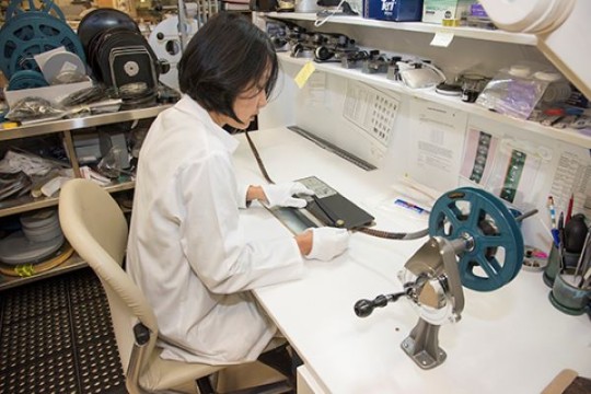 Woman working at a preservation desk with a film reel