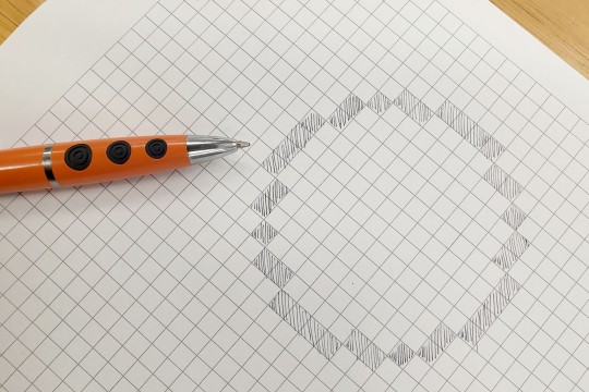 A photograph of a circle drawn on grid paper by colouring in squares.