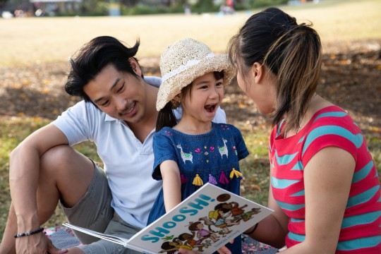 Family reading a book in the park