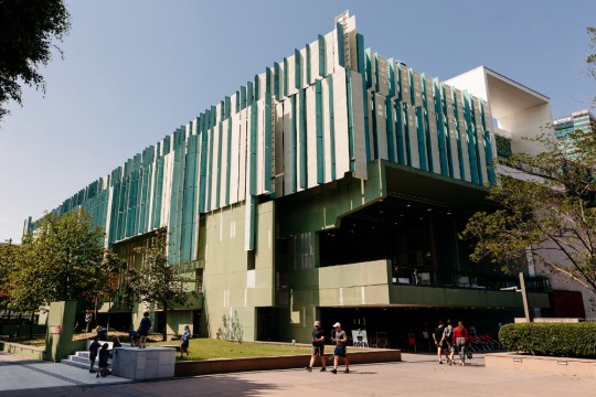 Exterior view of State Library building during the day with people walking in front of it 