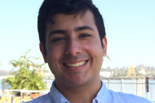 Photo of a young man smiling; a river is in the background