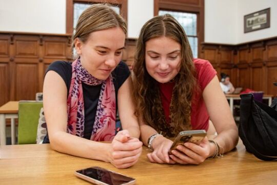 Young people looking at phone content at Cairns Public Library