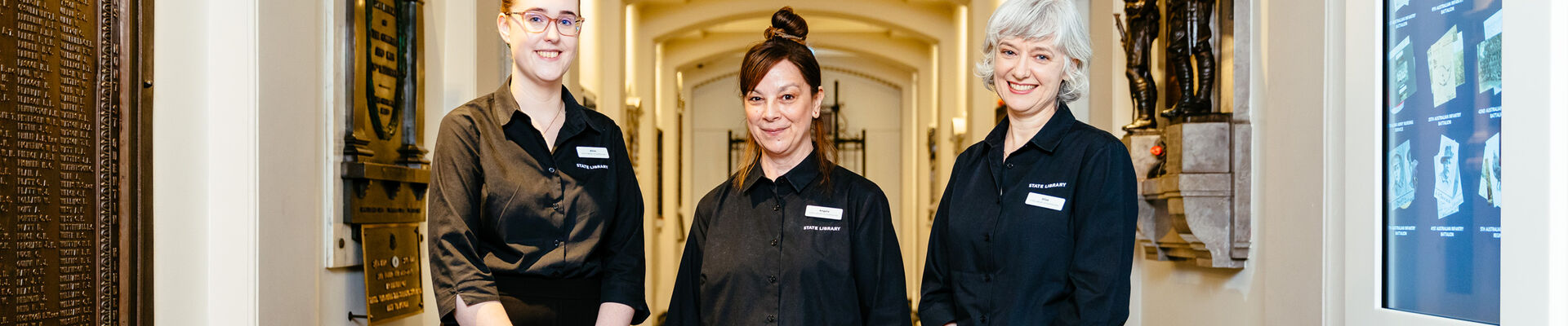 Three staff members at Anzac Square Memorial Galleries standing at the entrance to the World War I crypt