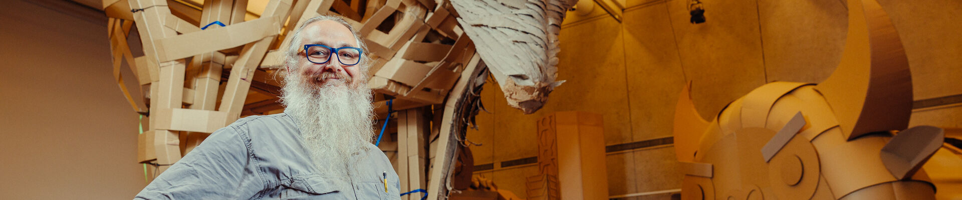 Man standing in front of giant cardboard sculptures