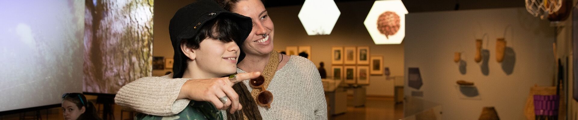 Mother with arm around teenage son at exhibition