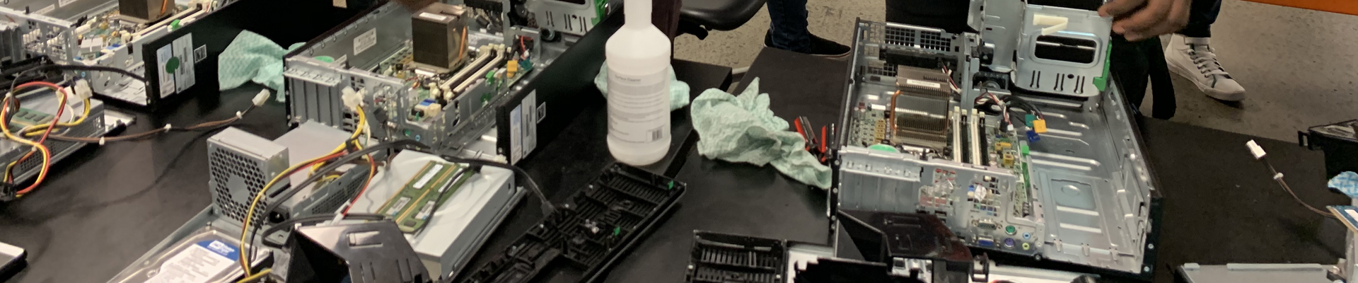 Three young men smiling and working on the inside of computer cpus
