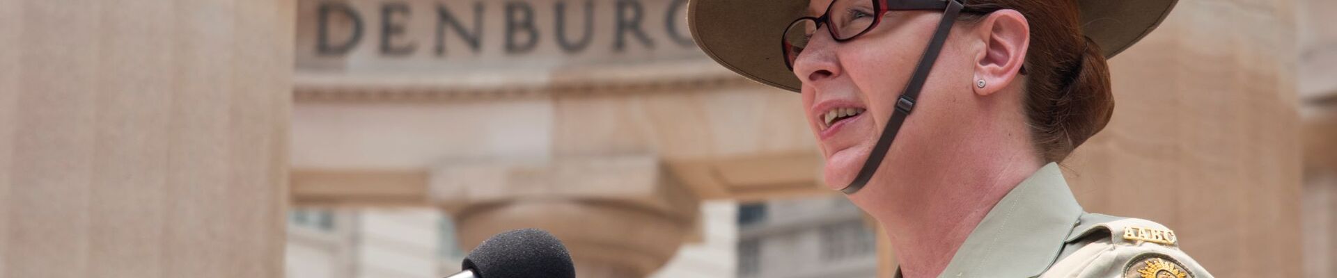 Defence force member speaking into a microphone at Anzac Square