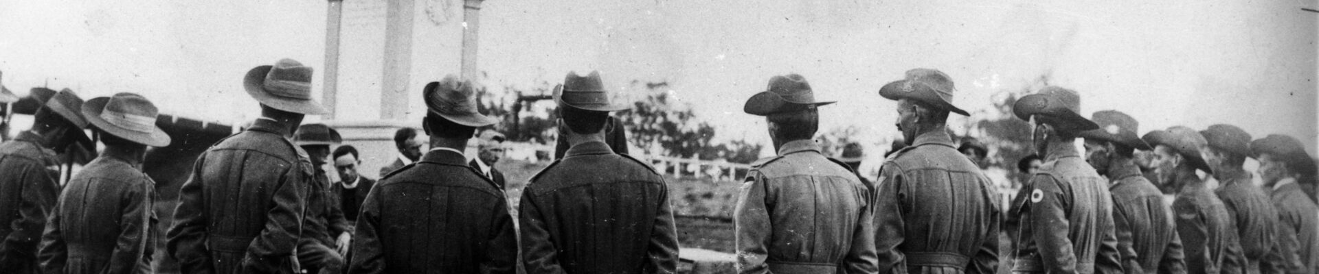 Returned soldiers in uniform surrounding the Digger War Memorial