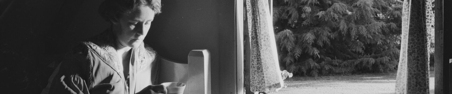 Woman lying in bed with a cup of tea at the High Tor guesthouse Woman lying in bed with a cup of tea at the High Tor guesthouse