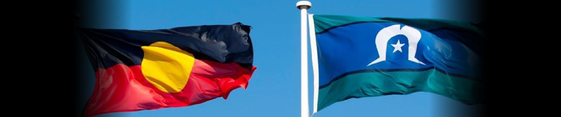 Aboriginal and Torres Strait Islander flags flying in a blue sky