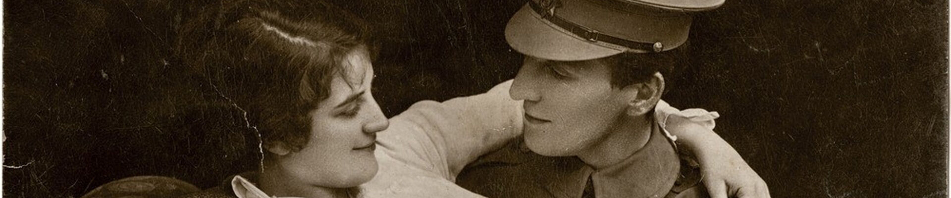 Postcard showing woman sitting on soldiers knee with her arm around his shoulder