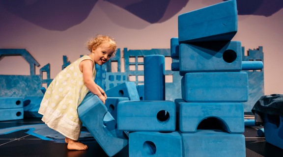 Young girl building with big blue blocks