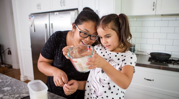 Mother and daughter cooking together in a kitchen.