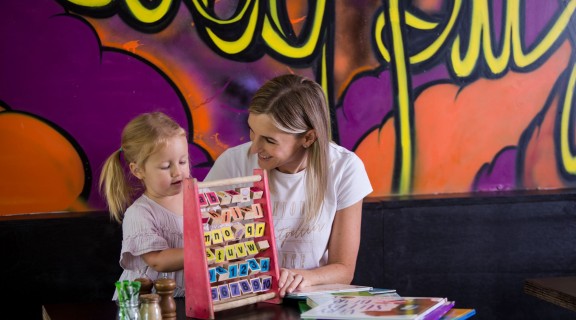 Mother and daughter playing with toy at cafe