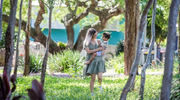 Mother holding child walking through garden
