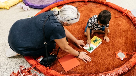 Caregiver and child reading a book about dinosaurs