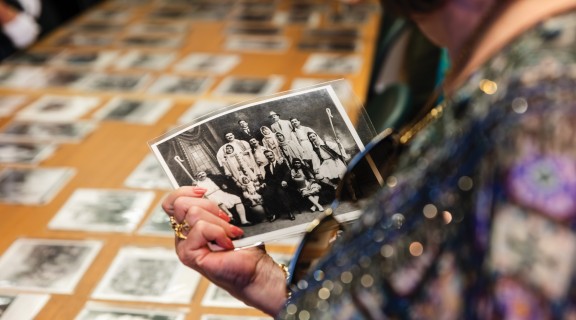 Person holding an old black and white photograph of a group of people.