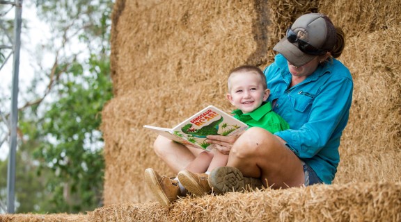 Mother and son reading book on hay bales