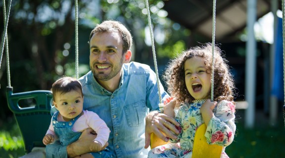 Father with two children playing on the swing, 2021, photography by Jason Henry, First 5 Forever image library, State Library of Queensland