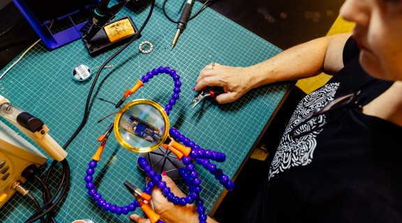 Someone soldering at an electronics bench 