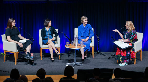 Panel of 4 people talking on a stage.