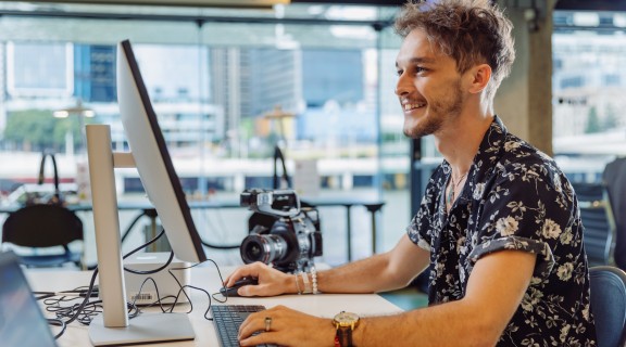 A young man working at a computer smiling