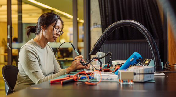 Woman participating in Electronics bench induction.