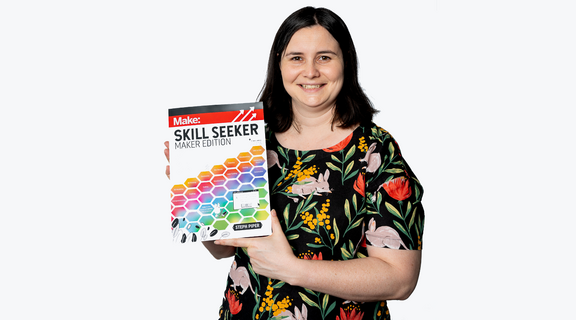 A photo of a woman holding a book called Skill Seeker; maker edition