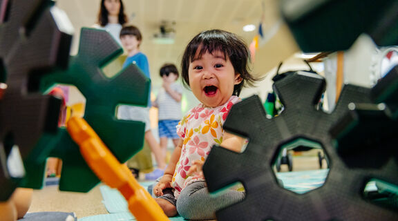 Toddler smiling as they play with construction cogs