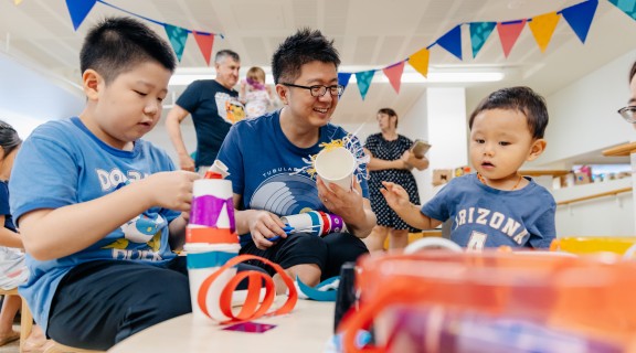 A parent and two children make crafts together.