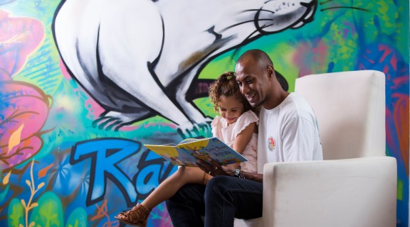 Father and daughter reading together in front of wall art